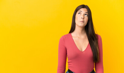 Teenager Brazilian girl over isolated yellow background and looking up