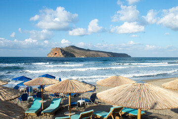 Crete, Agia Marina, Chania. Cretan beach scene at charming with parasols and sun beds on the beach.  Landscape aspect with copy space. - obrazy, fototapety, plakaty