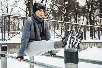 Athletic woman during her winter outdoor workout on parallel bars