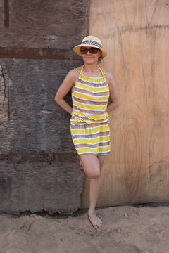 Lady in Yellow wearing a Straw Hat Posing Against a Rustic Wooden Background