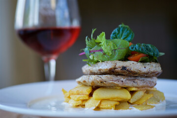 Pieces of fried meat lie on potatoes on a white plate. Decorated with vegetables and herbs. The concept of recipes from the restaurant and dishes from the chef.