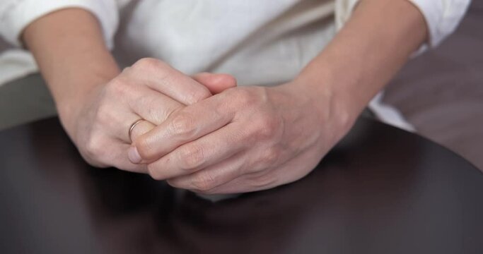Angry woman about marriage. A view of angry woman hands taking off her marriage ring in the room.