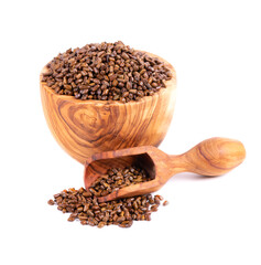 Cassia tora beans in olive bowl and scoop, isolated on white background. Sicklepod or Senna obtusifolia. Clipping path.