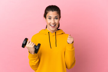 Young sport girl making weightlifting over isolated pink background celebrating a victory in winner position