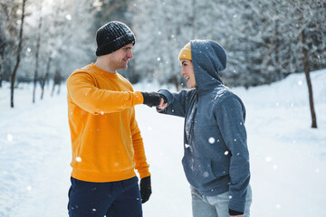 Two joggers greeting each other with a fist bump gesture during winter workout