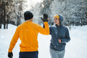 Two joggers greeting each other with a high five gesture during winter workout