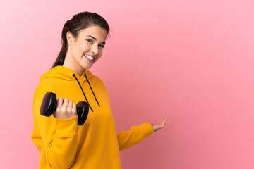 Young sport girl making weightlifting over isolated pink background extending hands to the side for inviting to come