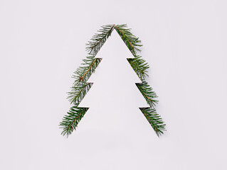 Christmas tree with fir or spruce pine branches against bright white background. Creative Xmas or New Year festive concept. Minimal winter composition with empty copy space for text. Flat lay.
