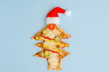 Delicious vegetarian Christmas tree pizza with tomatoes, vegetables and cheese on blue background. Creative, funny food concept for kids. Top view, flat lay. Copy space. Template. Mock up.