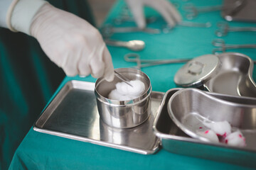 Nurse holding the surgical instrument with a cotton swab or peanut.