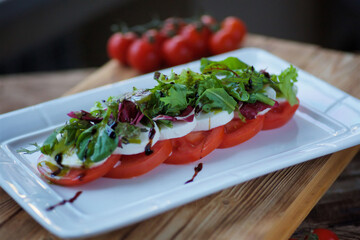 The dish is mozzarella cheese with tomatoes and sauce. Serving dishes