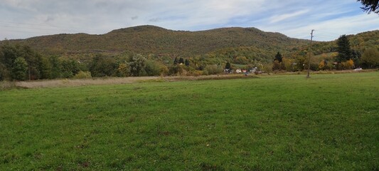 Obraz premium Beautiful panoramic view of the meadow and the hill with autumn trees.