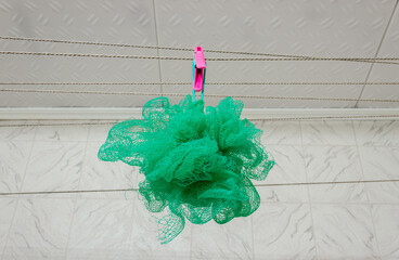 A green washcloth hangs on a clothesline in the bathroom. Cleanliness and hygiene concept