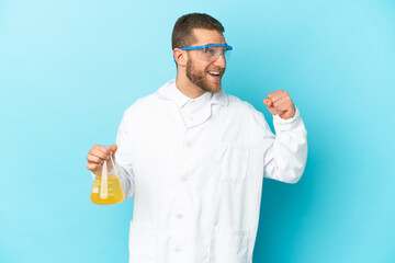 Young caucasian scientific man isolated on blue background celebrating a victory