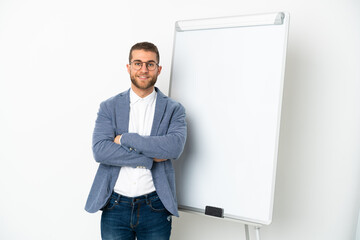 Young handsome caucasian man isolated on white background giving a presentation on white board and smiling