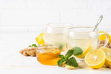 Ginger tea with lemon and honey in glass mug. Healthy hot vitamin drink at white background.