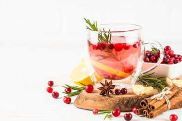 Cranberry tea with lemon and spices at white table. Healthy hot drink.