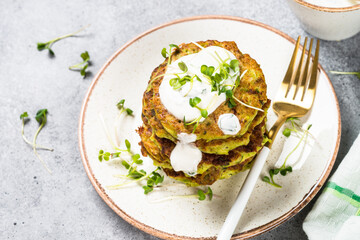 Zucchini pancakes with spinach, hepbs and parmesan cheese, served with sour cream or yogurt. Healthy Diet food, meatless dish.