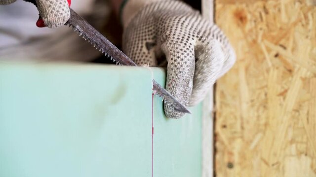 Worker Cutting Plasterboard With Handsaw