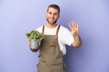 Gardener caucasian man holding a plant isolated on yellow background happy and counting four with fingers