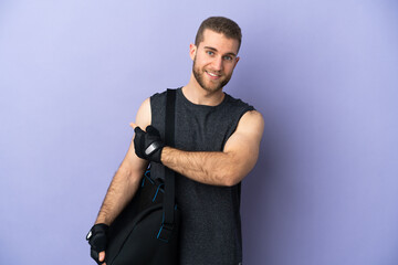 Young sport man with sport bag isolated on white background pointing back