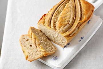 homemade banana bread on a wooden board on a table with a tablecloth