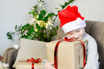 A boy is hugging his a christas presents. He is happy. Horizontal frame.