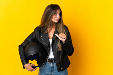 Woman holding a motorcycle helmet isolated on yellow background proud and self-satisfied