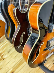 Obraz premium detail of several electric guitars and bass guitars placed on a guitar stand, viewed from the side, semi hollow body electric guitar