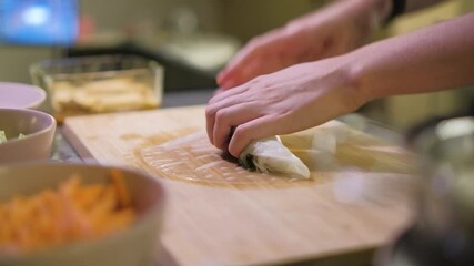 A chef preparing fresh Vietnamese spring rolls on a wooden board, shot in 4K