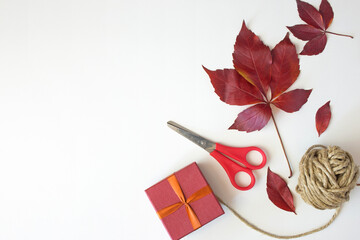 Christmas composition of a red gift , ribbon and scissors on a gray white background. Top view,...