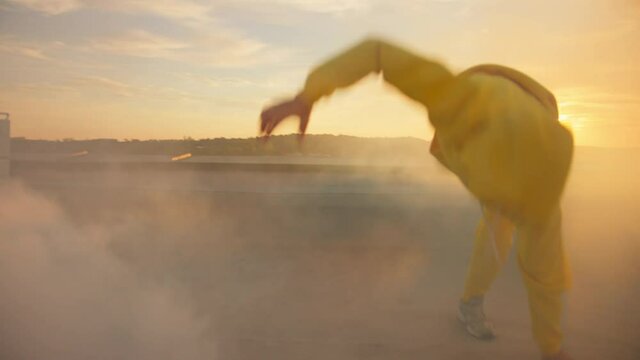Handsome stylish hip hop guy dancing street breakdance in smoke on the rooftop. Talented active bboy man performing various freestyle dance moves. Artist performance. Entertainment.