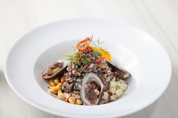 Black ceviche with shell, very typical in Peru. on white plate.
