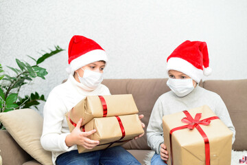 Two boys are holding his christmas presents. They are in the masks. Coronovirus. Horizontal frame.
