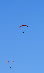 People paragliding on Santa Pola coast under blue sky