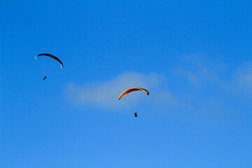 People paragliding on Santa Pola coast under blue sky