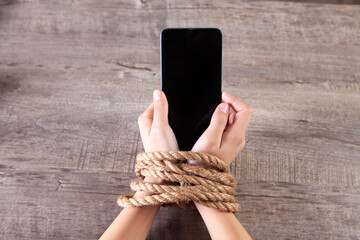 tied with a rope female hands hold the phone