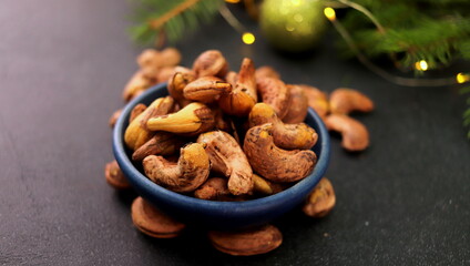 roasted cashews in a peel in a bowl close-up on a dark background selective focus.