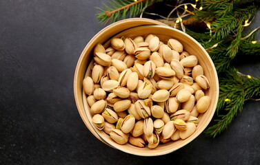 Pistachio nuts in a bowl close-up on a dark background selective focus.