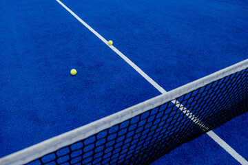 Top view of a net of a blue paddle court and two balls