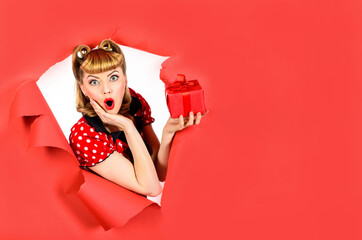 Amazed girl with gift breaking paper. Surprised retro woman hold gift box through hole in paper....