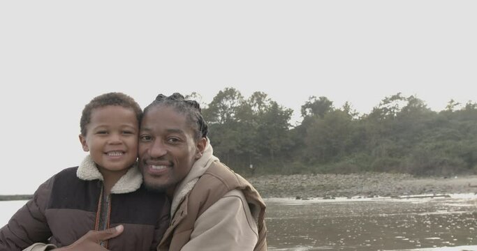 Father and toddler looking at camera on beach holiday