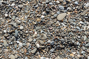 The original texture background of the sea beach, pebbles of different sizes, round and oval. The stones are gray, white and brown. Natural pattern, close-up