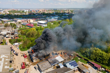 Aerial view of firefighters extinguishing ruined building on fire with collapsed roof and rising...
