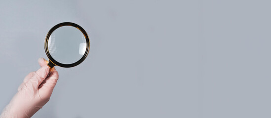 Medical hand in glove with magnifying lens, finding and examining medicine. Banner with copy space...