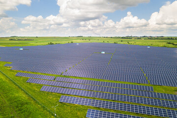 Aerial view of solar power plant on green field. Electric panels for producing clean ecologic energy.