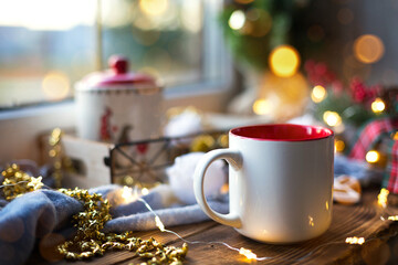 Christmas decor by the window on a cozy wooden windowsill with a mug with a drink and a cookie jar....