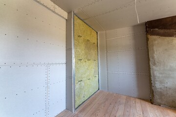 Wall of a room under renovation with mineral rock wool insulation and metal frame prepared for...