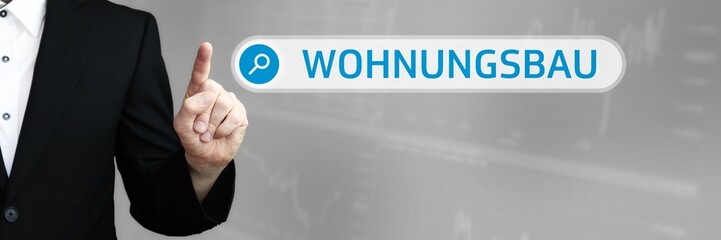 Fototapeta premium Wohnungsbau. Mann zeigt mit Finger auf Suchfeld im Internet-Browser. Wort/Text (blau) in der Suche.