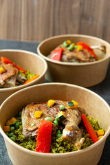 Arroz con pato, a typical Peruvian dish, in a pot on a gray background.
